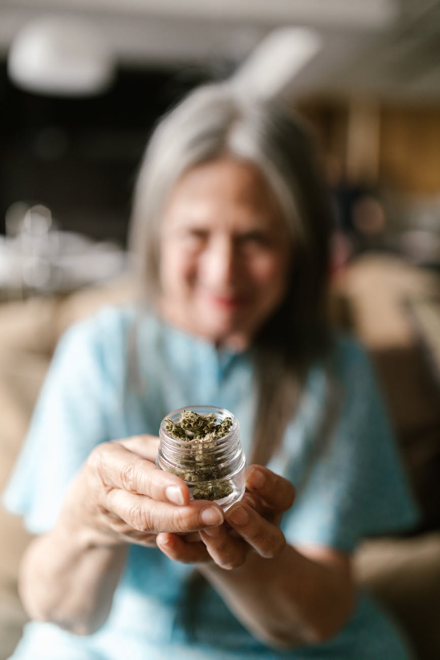 a woman holding a glass container with dry leaves